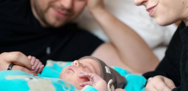 Vanhemmat katselevat nukkuvaa vastasyntynyttä.