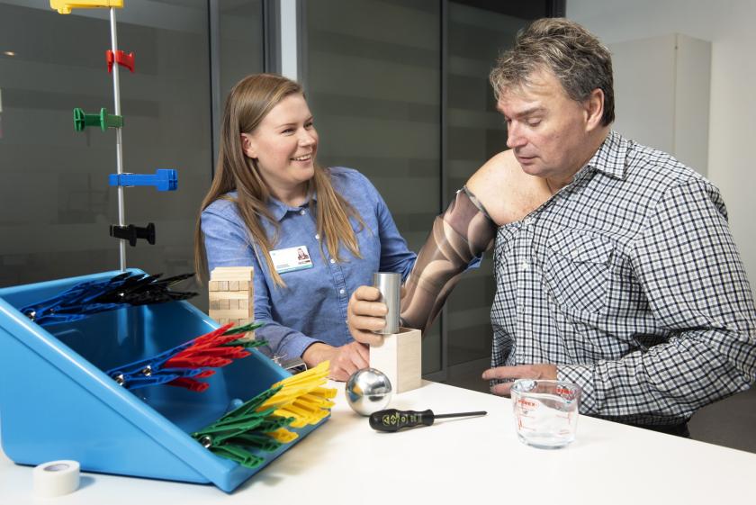 Kuvituskuva: apuvälineterapeutti kuntouttaa potilasta, jolla on proteesikäsi