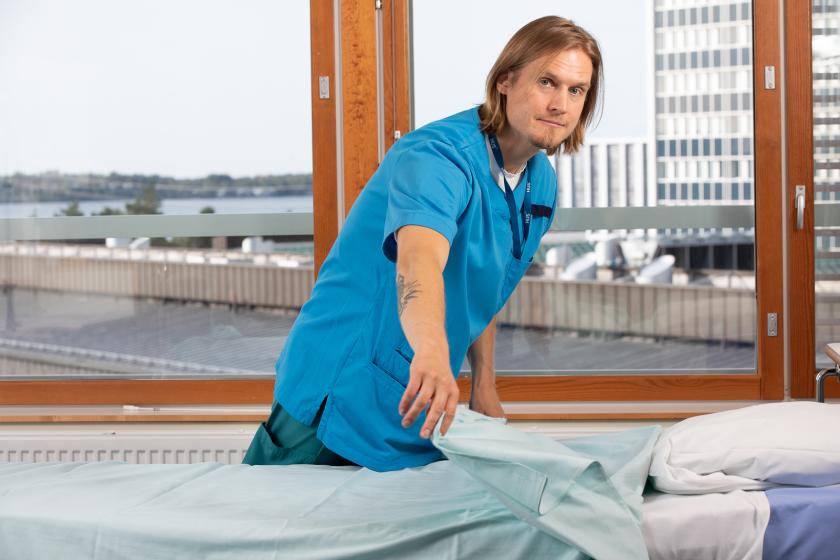 Hoitaja petaa sänkyä.