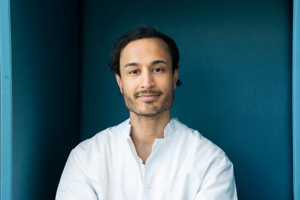 Rahul Raj lääkärintakissa tummansinistä taustaa vasten.