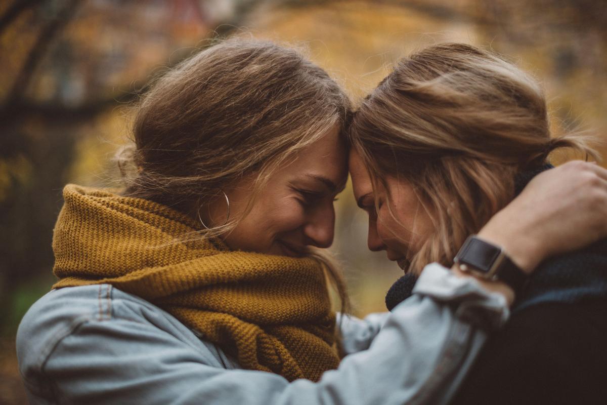 Kaksi naista otsat vastakkain lähikuvassa syksyisessä luonnossa.