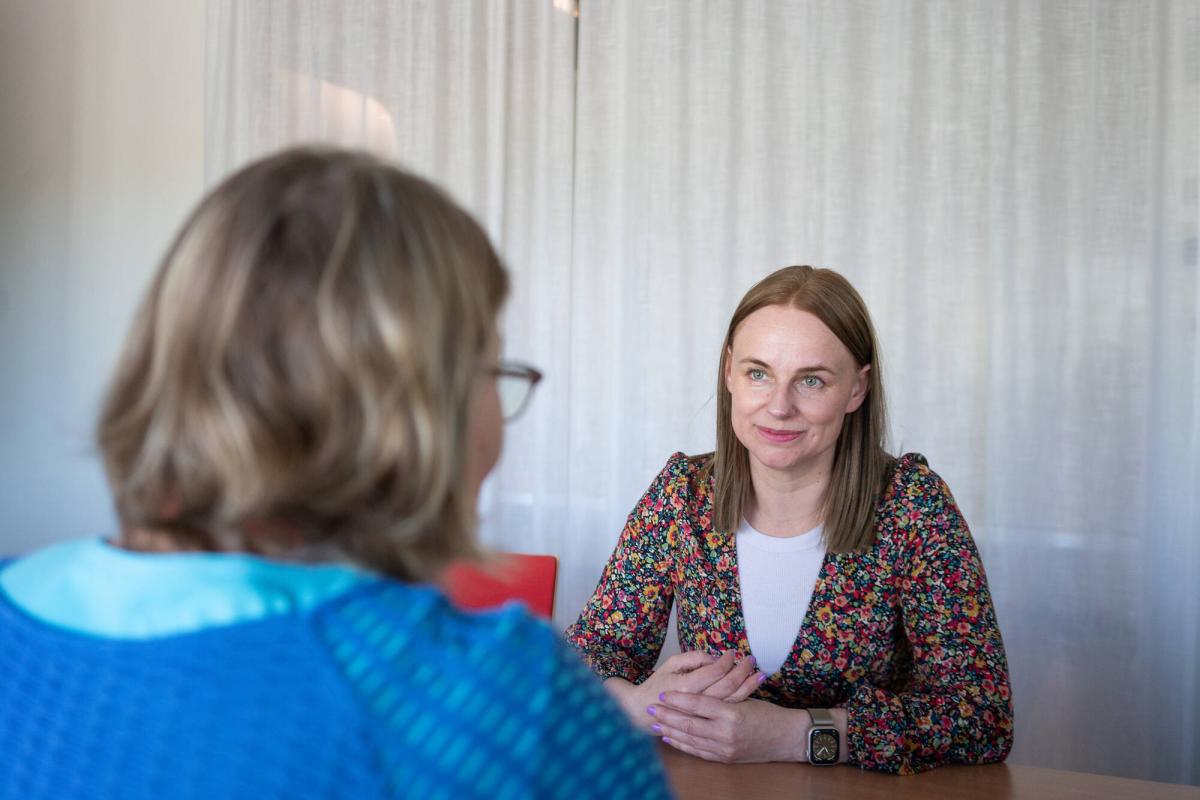 Kaksi henkilöä keskustelee pöydän ääressä.