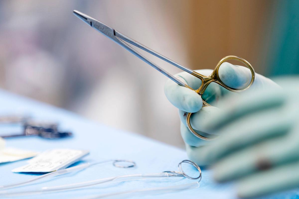 Sakset kirurgin kädessä leikkaussalissa.