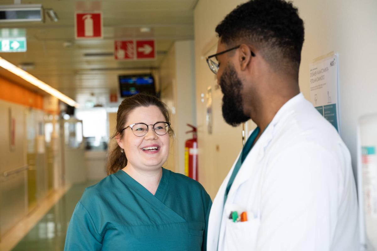 Lääkäri ja hoitaja keskustelevat sairaalan käytävällä.