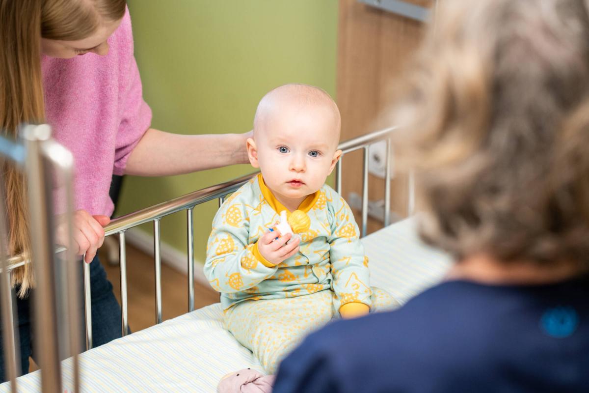 Vauva istumassa sairaalasängyssä.