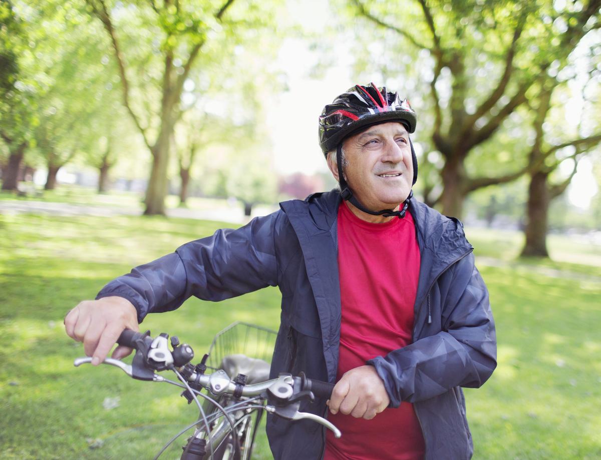 Vanhempi miesoletettu pyörän kanssa kesäisessä puistossa.