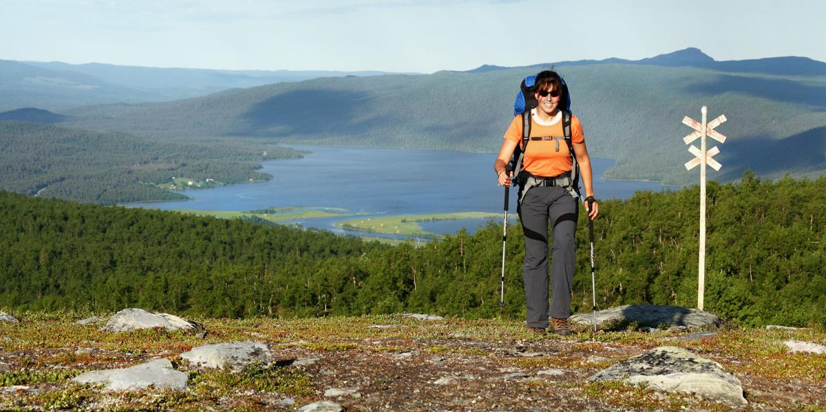 Nainen vaeltaa kukkulaisessa maastossa.