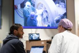 kaksi lääkäriä katsoo ruudulta leikkausta luentosalissa.