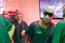 vierailija leikkaussaleissa katsoo leikkausta mustilla laseilla.