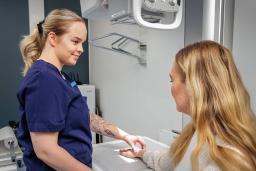 Hoitaja valmistelee potilaan käden röntgenkuvausta.