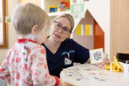 Varhaiskasvatuksenopettaja Satu Laakso leikkii lapsen kanssa kuvakorteilla leikkiosastolla.