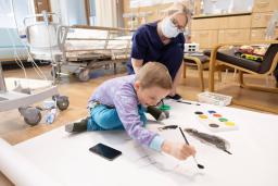 Lapsi maalaa sairaalan leikkiosastolla.