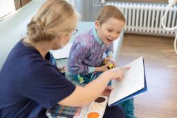 Varhaiskasvatuksen opettaja ja lapsi piirtävät sairaalan leikkiosastolla.