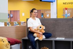 Nainen istuu sohvalla sylissään keltainen pehmonalle.