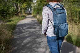 Ihminen kävelemässä luonnossa infuusiopumppureppu selässään.