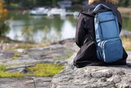 Ihminen istumassa kalliolla infuusiopumppureppu selässään.