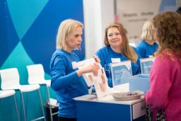 Kaksi naista esittelee messutiskillä HUSin toimintaa.